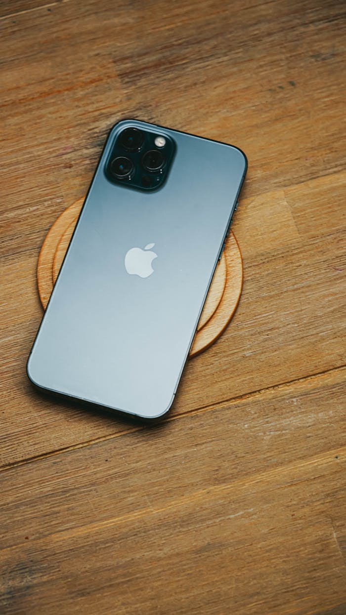 High-angle view of a sleek smartphone resting on a wooden table, showcasing modern technology design.
