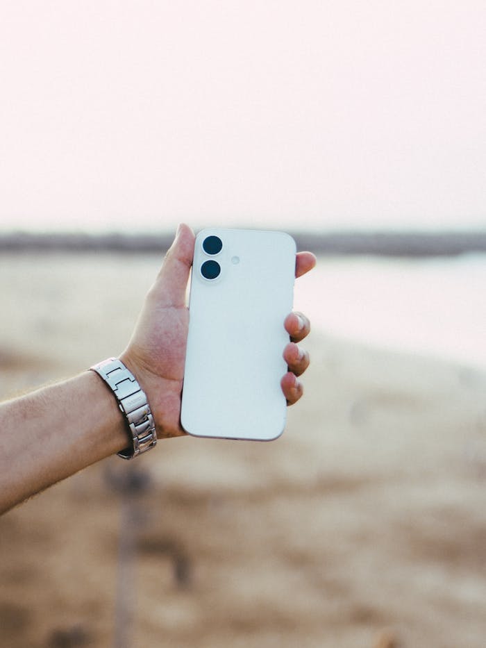 our-mission A hand holding a white smartphone at the beach in Rabat during daytime, showcasing modern technology.